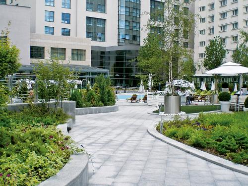 Curved walkways, plant beds and swimming pool surrounded by parasols and sun beds